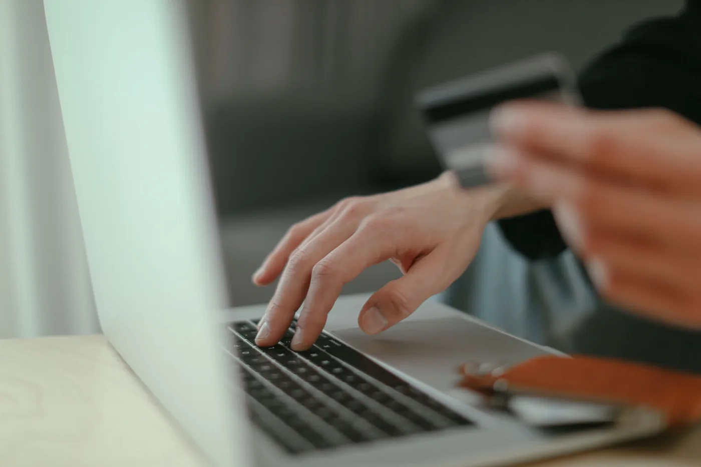 Nahaufnahme einer Hand auf einem Laptop, während eine Karte gehalten wird.