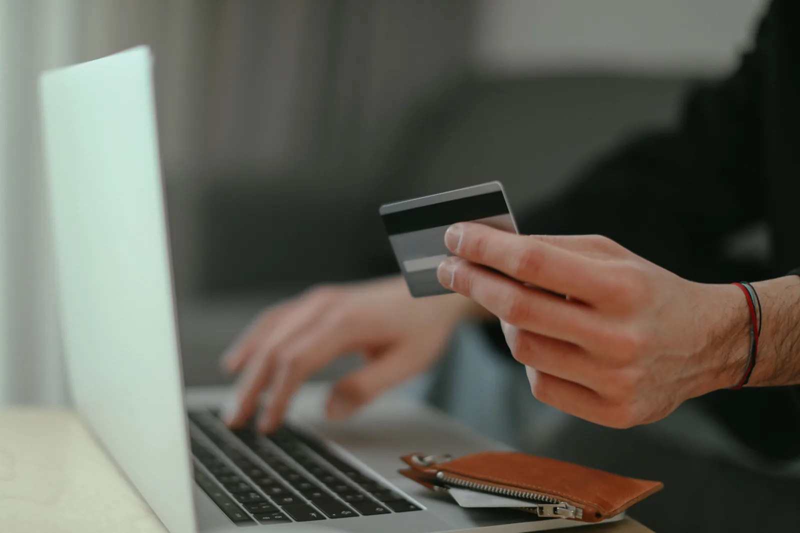 Person bezahlt online mit Karte und nutzt dabei einen Laptop.
