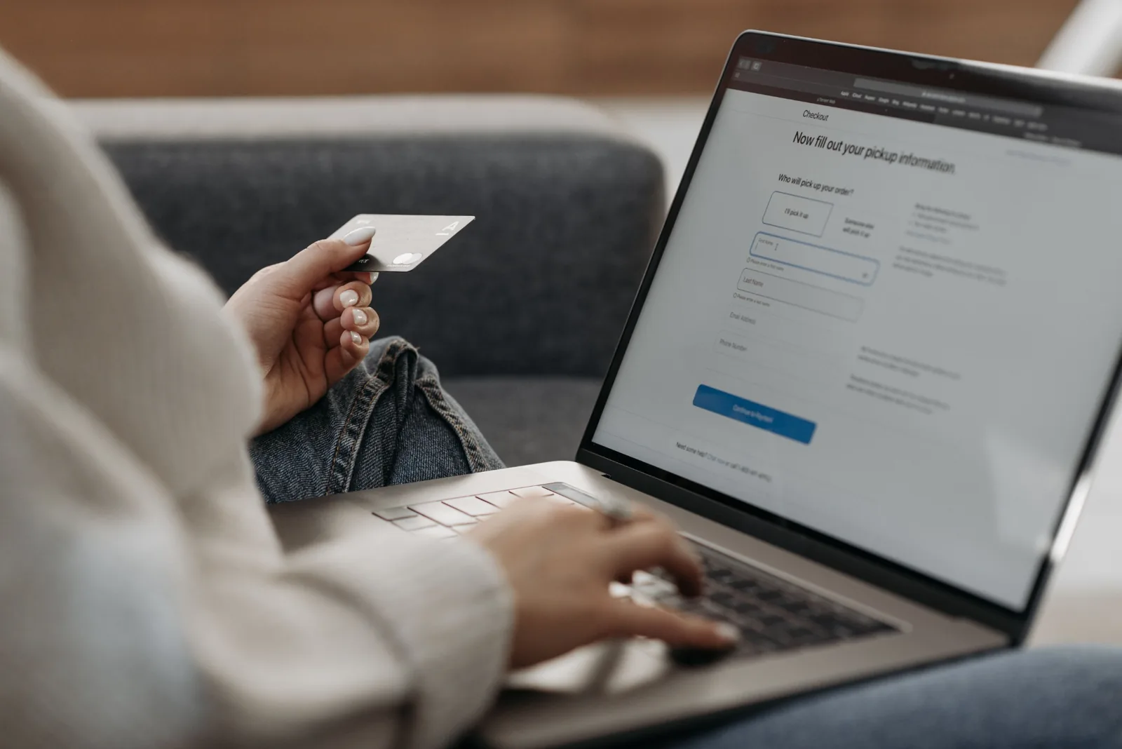 Person shopping online from a sofa with a laptop and card.